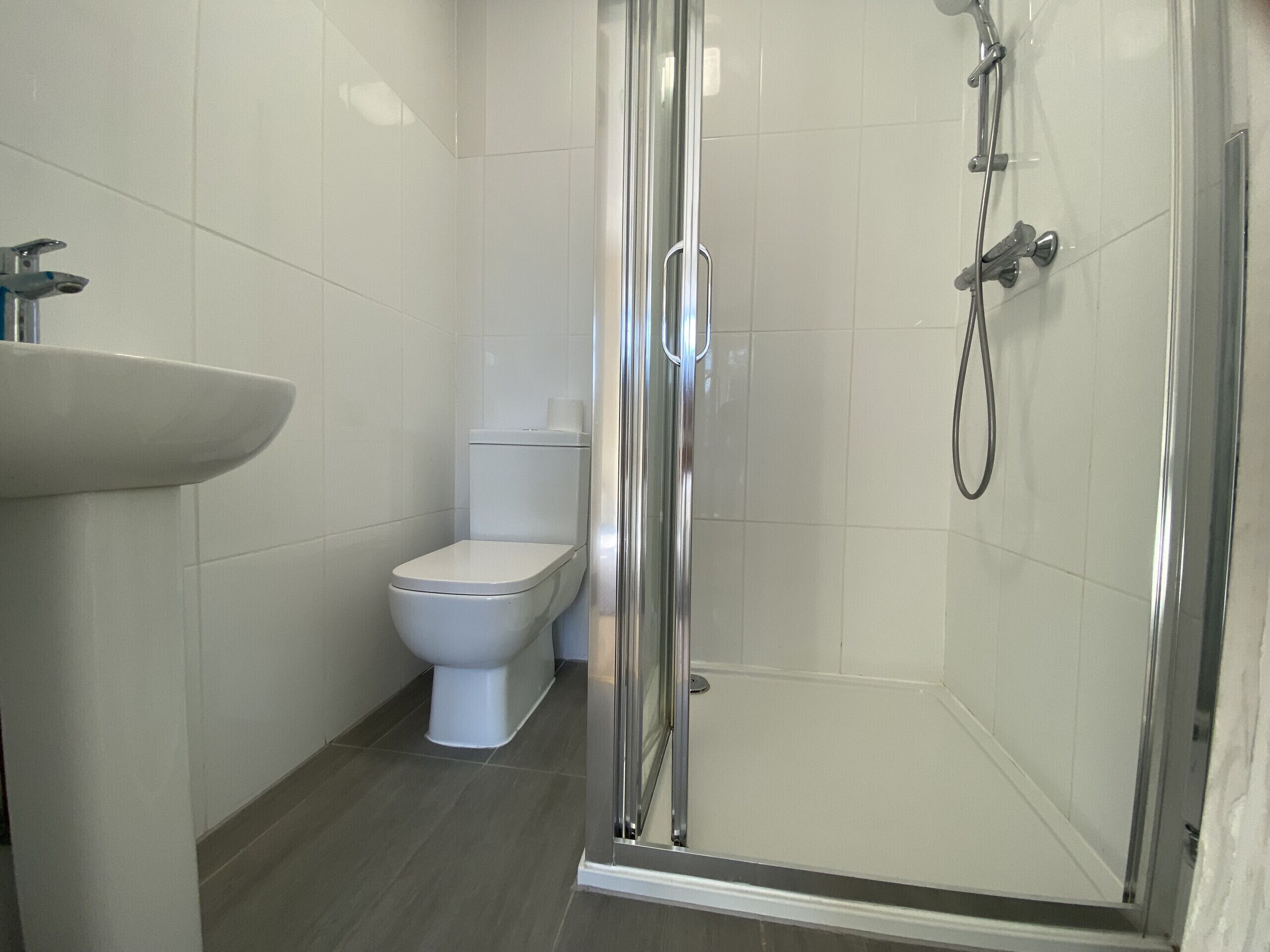 A bathroom with a glass-enclosed shower, a white toilet, and a sink.