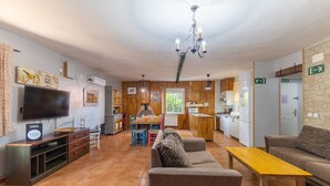 Una sala de estar con televisor, sofá, mesa de comedor de madera y candelabro.