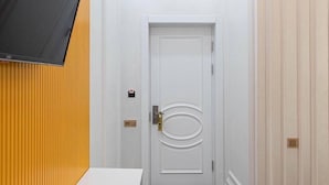 A narrow hallway with a white door, a yellow wall on one side, and a white wall on the other. - ARDANI Hotel  (Samarkand)