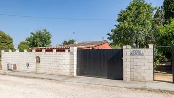 Propiedad amurallada con muro de ladrillo, portón metálico y un letrero que dice 'FINCA MTLFLORES'.