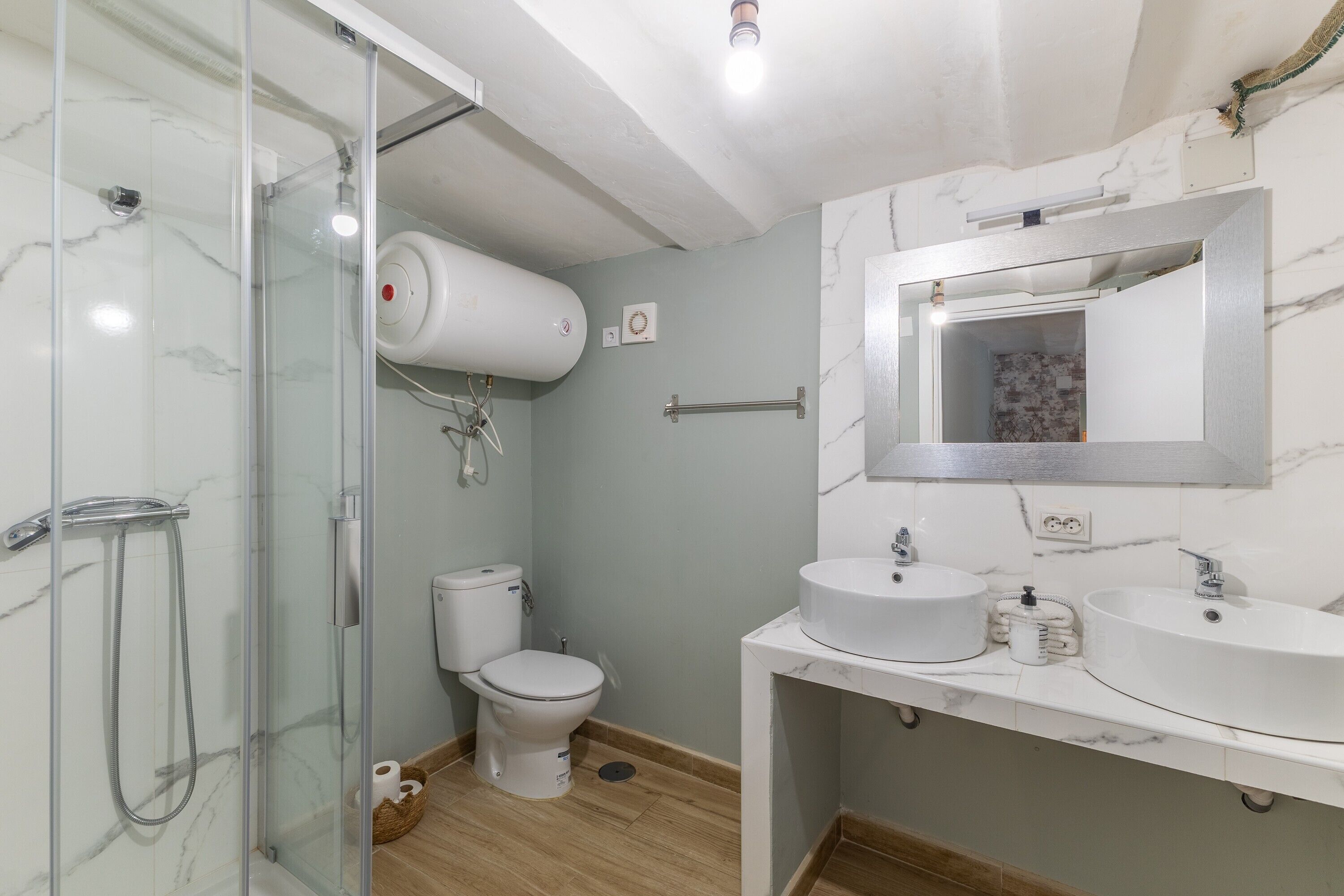 Une salle de bain avec une douche à parois de verre, des toilettes, un lavabo avec un miroir et un porte-serviettes.