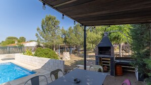 Zona exterior coberta amb piscina, barbacoa i seients.