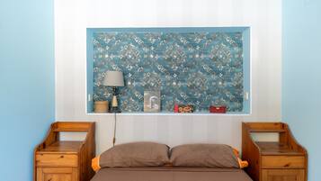 Un dormitorio con una cama, dos mesitas de noche de madera, una lámpara y un panel decorativo en la pared.