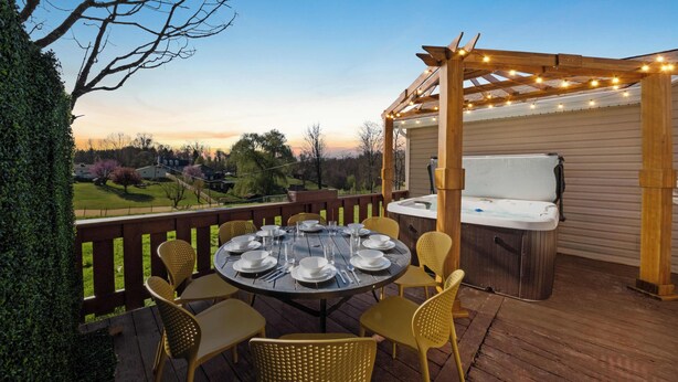 A wooden deck with a round table set for dining, surrounded by chairs. - Adventure Basecamp, Walks to Kaymoor and Long point Trails, Hot Tub & Game Room (Fayetteville)