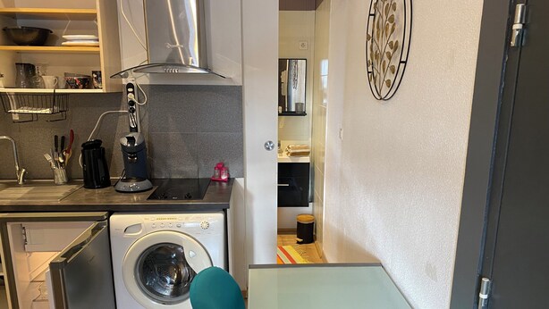Une cuisine compacte équipée d’un lave-linge, d’une machine à café et d’un four à micro-ondes.
