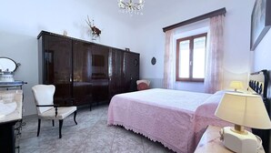 A bedroom with a bed, a chair, a desk, a wardrobe, and a window with curtains. - La Terrazza sul Borgo (Capoliveri)