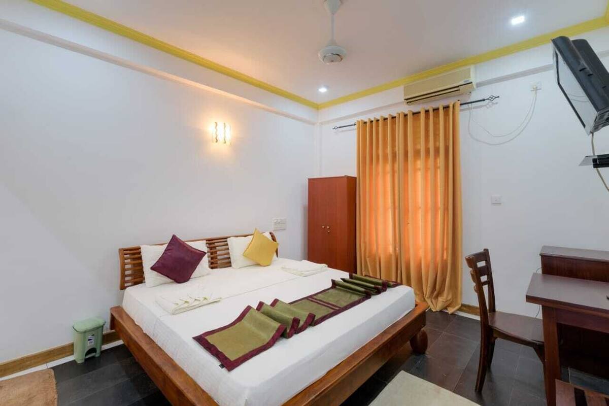 A bedroom with a bed, a desk, a chair, a wardrobe, and a curtain.