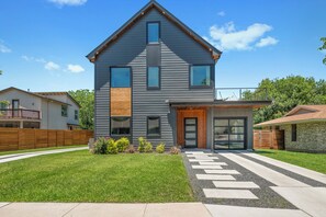Une maison moderne à deux étages, dotée d’une grande véranda à l’avant, d’un garage et d’une pelouse bien entretenue.