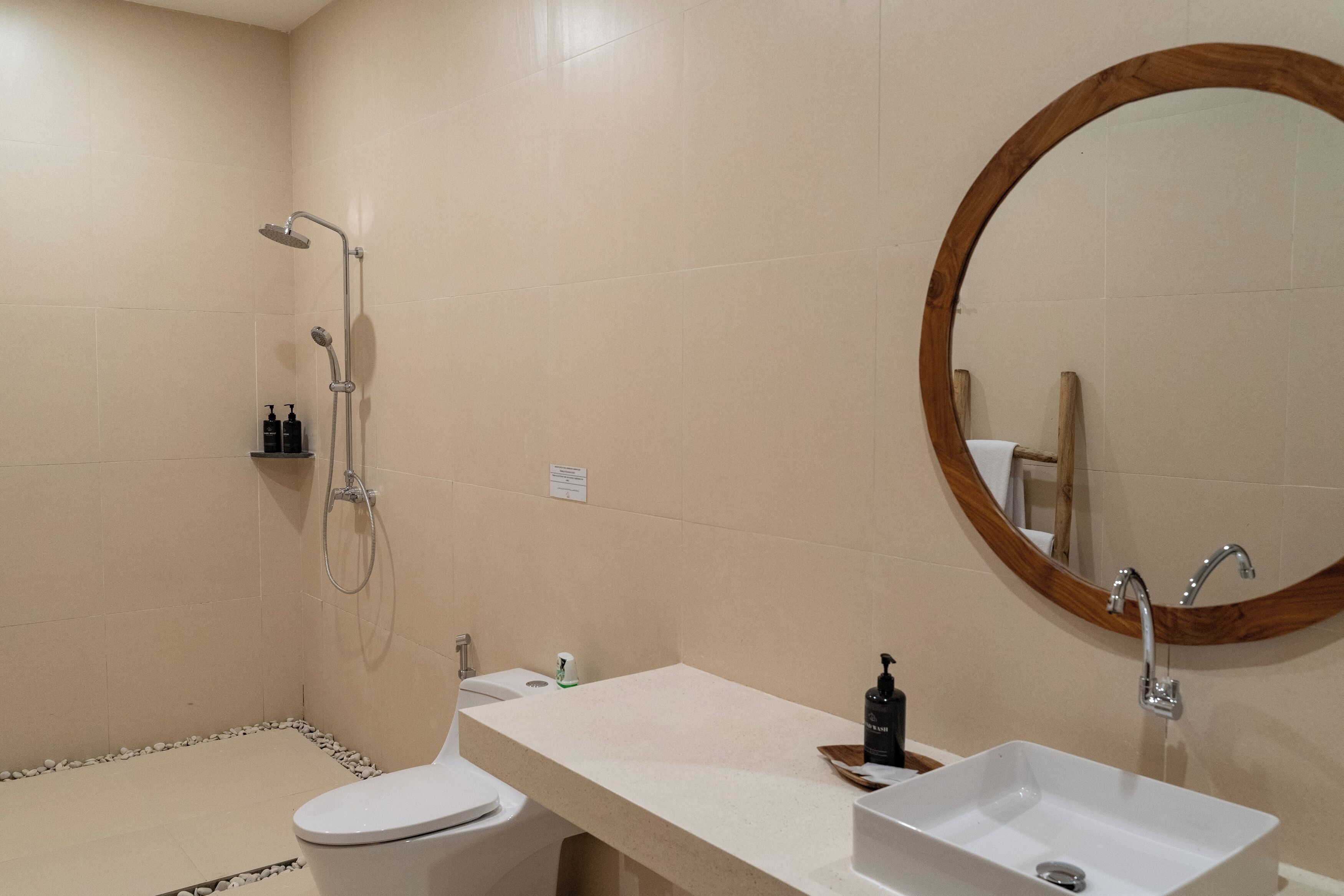 Un baño con ducha, inodoro, lavamanos y un espejo de marco de madera.