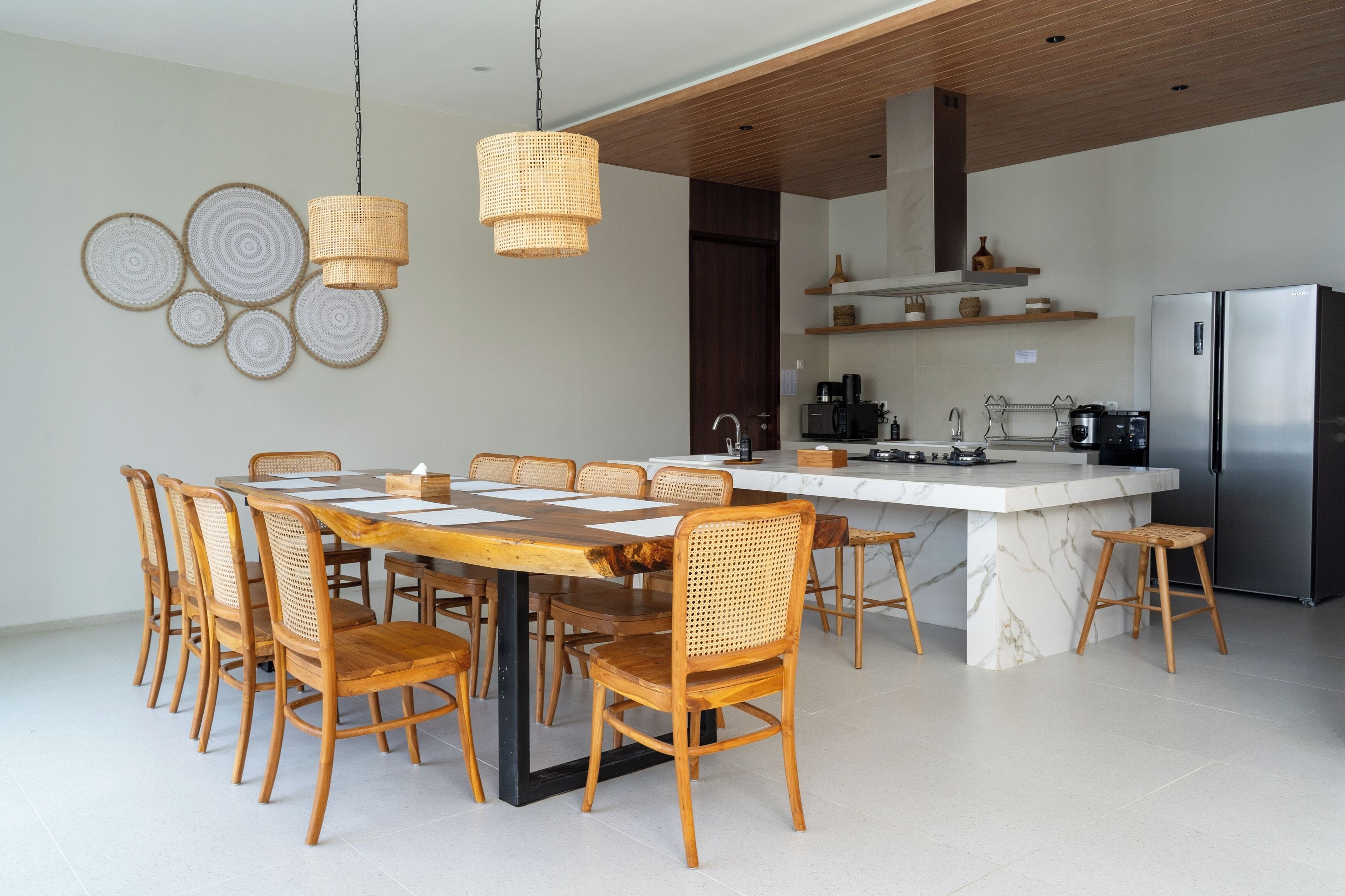 Una cocina moderna con una isla grande, sillas de madera y una lámpara colgante.
