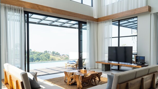 Un soggiorno moderno con una grande TV, posti a sedere confortevoli e vista su un ponte e zone verdi.