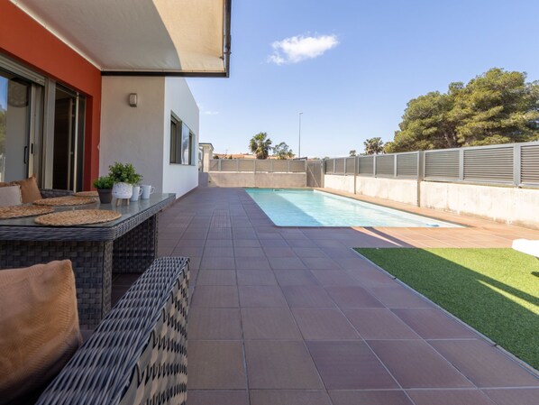 Ein moderner Poolbereich im Freien mit Terrasse, Sitzgelegenheiten und Blick auf die umliegende Landschaft.