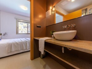 Ein modernes Badezimmer mit einem großen, weißen Waschbecken, einem Spiegel und einem Fenster.
