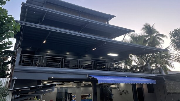 A multi-story building with a covered outdoor area, a staircase, and a blue awning. - Lucky Tito Diving Inn Coron (Coron)