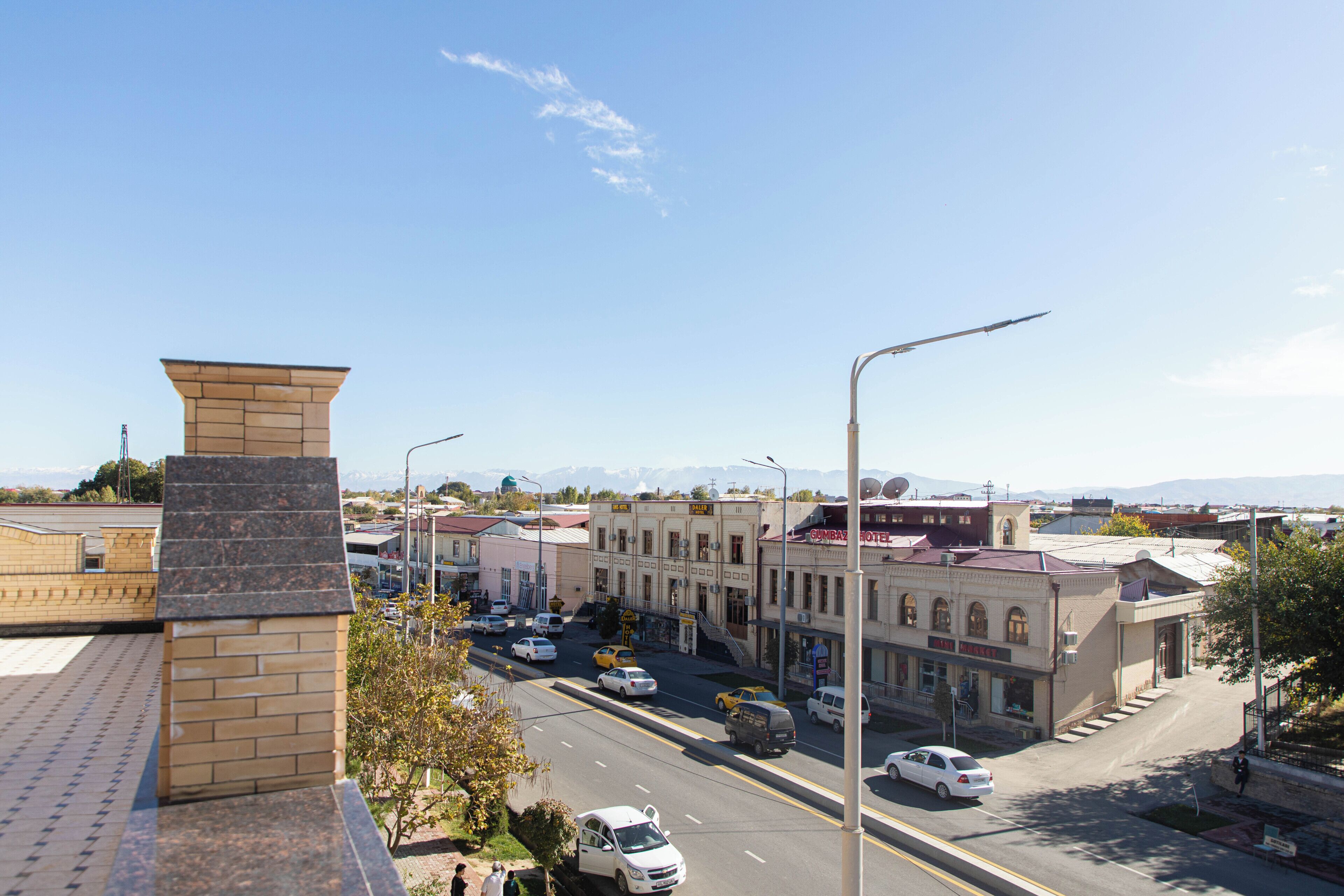 A street view with buildings, a clear sky, and a mountain range in the distance.
