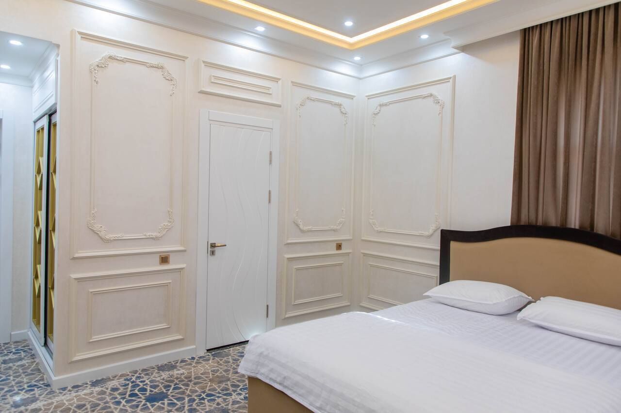 Una camera da letto con un letto, pareti bianche e un pavimento decorato.