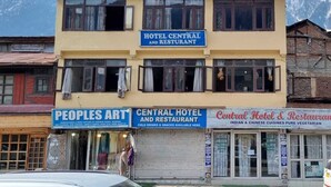 Un edificio de varios pisos con letreros que indican Hotel Central y Restaurante, Artes Populares y Hotel & Restaurante Central.