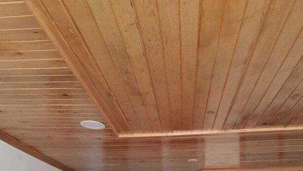 Un pasillo con vigas de madera en el techo, una puerta a la izquierda y un ventanal a la derecha.