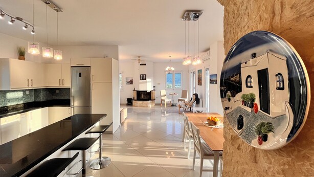 A modern kitchen with a black countertop, stainless steel appliances, and pendant lighting. - Villa Francesca, Greek Garden Getaway in Agia Galini (Agia Galini)