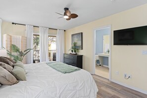 A bedroom with a bed, a dresser, a TV, a ceiling fan, and a view of the outside.