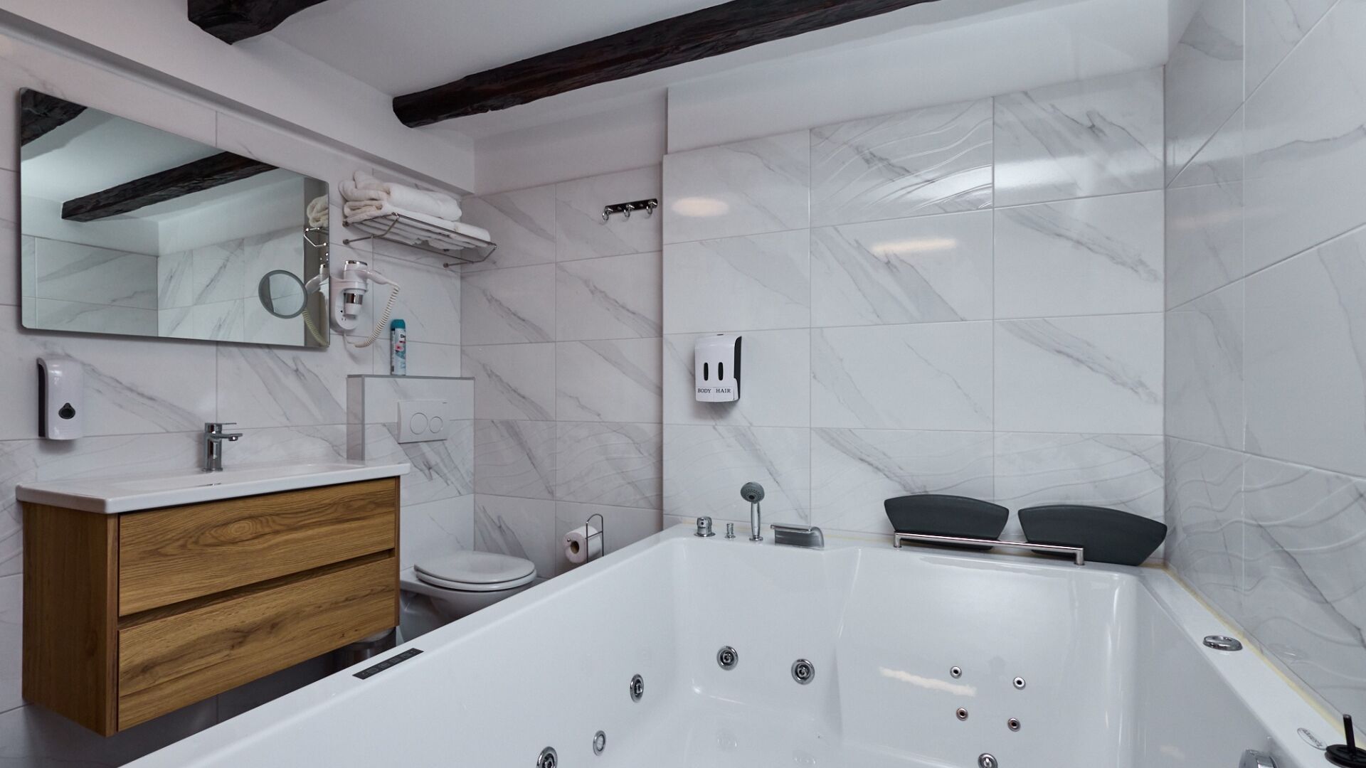 Een moderne badkamer met een marmeren wand, een houten wastafelmeubel, een bad en een spiegel.