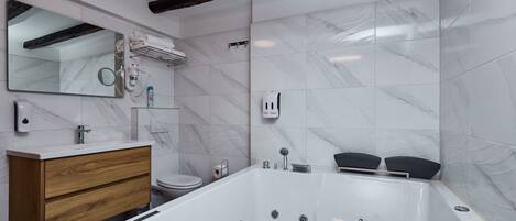 Een moderne badkamer met een marmeren wand, een houten wastafelmeubel, een bad en een spiegel.