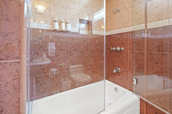 Un baño moderno con cabina de ducha de vidrio, bañera blanca y paredes de mármol.