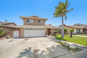 A two-story house with a garage, a front lawn, and a palm tree. - 5 BR Jacuzzi Disney Knotts Beach (Norwalk)