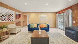 A spacious living room with a blue sofa, a wooden coffee table, and a patterned rug. - 5 BR Jacuzzi Disney Knotts Beach (Norwalk)
