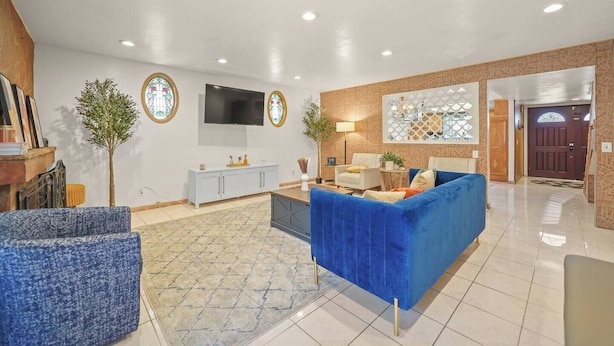 A spacious living area with a blue sofa, a white cabinet, and a TV mounted on the wall. - 5 BR Jacuzzi Disney Knotts Beach (Norwalk)