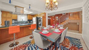 A modern kitchen with wooden cabinets, a stainless steel refrigerator, and a dining area with a table set for six. - 5 BR Jacuzzi Disney Knotts Beach (Norwalk)