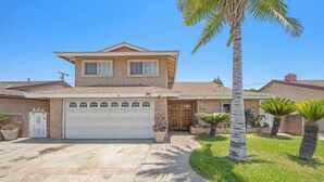 A two-story house with a garage, a front door, and a driveway leading to the garage. - 5 BR Jacuzzi Disney Knotts Beach (Norwalk)
