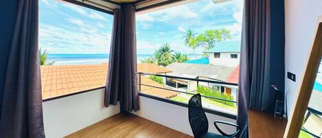 Una habitación con ventanas amplias, piso de madera y una silla negra.