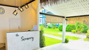 Un área de recepción con un letrero que dice “The Scenery”, un reloj y vistas a un jardín.