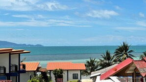 Vista costera con cielo despejado, una playa y varios edificios con tejados rojos.
