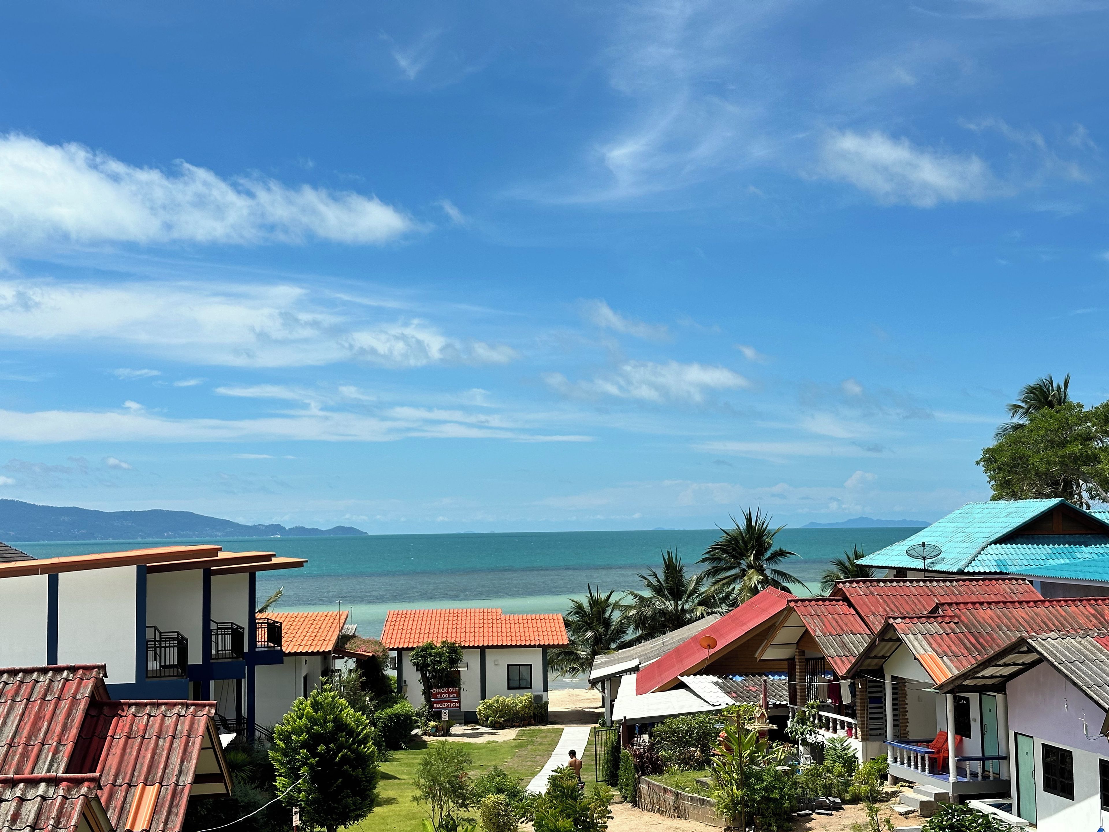 A coastal hotel with multiple buildings, a beach view, and a clear sky.