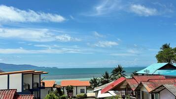 A coastal hotel with multiple buildings, a beach view, and a clear sky.