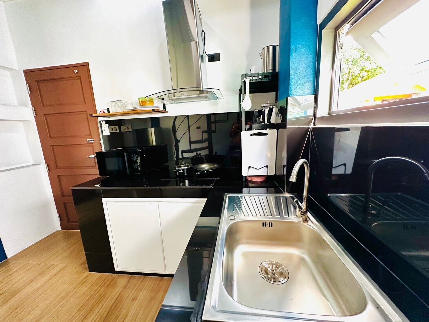 Een kleine keuken met een spoelbak, fornuis en magnetron.