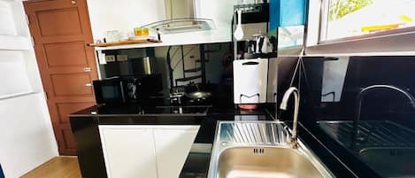 Een kleine keuken met een spoelbak, fornuis en magnetron.