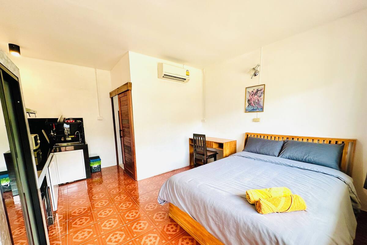 A bedroom with a bed, a desk, and a chair.