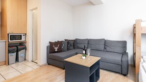 Un salon moderne avec un canapé gris, une table basse en bois, un four à micro-ondes et une poubelle.