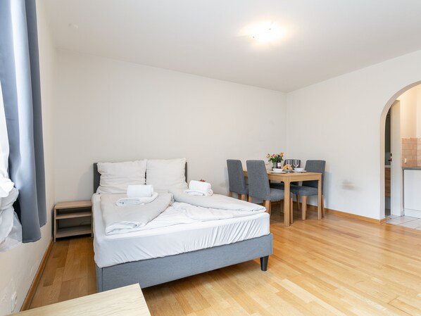 A hotel room with a bed, a small table with chairs, and a dining area.