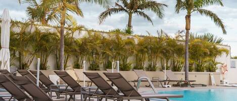 A poolside area with lounge chairs and palm trees.