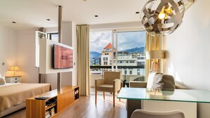 A modern hotel room with a bed, a TV, a desk, and a view of the cityscape. - Golden escape in Funchal (Funchal)