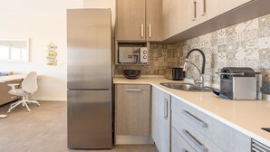A modern kitchen with a stainless steel refrigerator, wooden cabinets, a built-in oven, a toaster, and a coffee machine. - GuestReady - Seaview in Costa da Caparica (Almada)