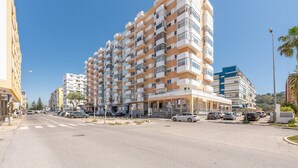 A multi-story hotel with balconies, a parking area, and a clear sky. - GuestReady - Seaview in Costa da Caparica (Almada)