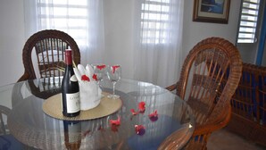 Una mesa de comedor con una botella de vino, copas y un posavasos tejido.