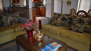 Una sala de estar con un sofá, una mesita de centro y una cocina al fondo.
