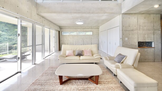 A spacious living room with a high ceiling, large windows, and a modern design. - Guest House Karst (Motobu)