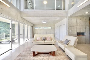 A spacious living room with a high ceiling, large windows, and a modern design. - Guest House Karst (Motobu)